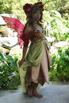 a woman dressed as a fairy standing in front of some plants