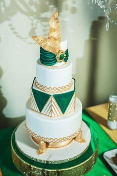 a three tiered cake with green and gold decorations