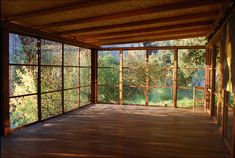 an empty room with wooden floors and large windows on the wall, overlooking trees in the distance