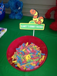 a red bowl filled with gummy bears next to a sign that says slimey's gummy friends