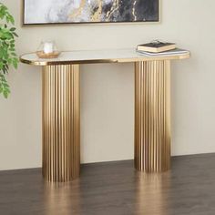 a gold console table with two books on top and a plant in the corner next to it