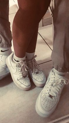 two people standing next to each other wearing white shoes