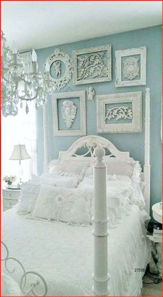 a white bed sitting in a bedroom next to a window with pictures on the wall