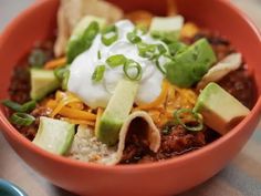 a bowl filled with chili, cheese and avocado on top of a table