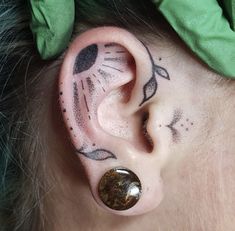 a close up of a person's ear with tattoos on it