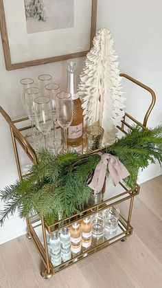 a bar cart filled with bottles and glasses on top of a hard wood floor next to a christmas tree