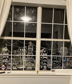 a window decorated with christmas lights and snowflakes is shown in front of a curtained window