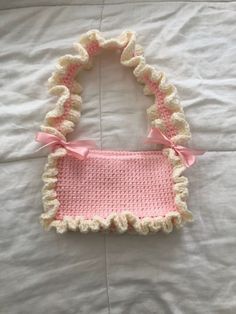 a crocheted purse with a pink bow on the side and white fabric around it