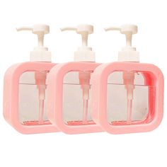 three pink soap dispensers sitting next to each other