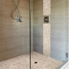 a walk in shower sitting next to a tiled wall with a glass door on the side