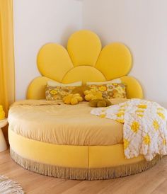 a large yellow bed sitting on top of a wooden floor next to a white wall