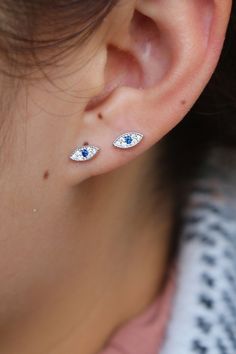 A woman wearing evil eye stud earrings. Dainty Sapphire Jewelry With Diamond Accents, Blue Birthstone Gold-plated Jewelry, Blue Birthstone Jewelry In Gold Plated, Blue Diamond Jewelry With Diamond Eyes, 14k Gold Blue Jewelry With Diamond Accents, Blue Gold-plated Birthstone Jewelry, 14k Gold Jewelry With Blue Diamond Accents, 14k Gold Jewelry With Diamond Accents In Blue, Dainty Blue Sapphire Jewelry