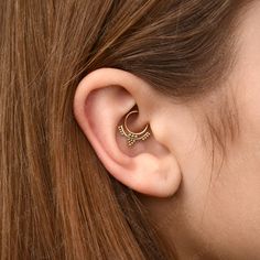 a close up of a person's ear with an earring in the shape of a crescent