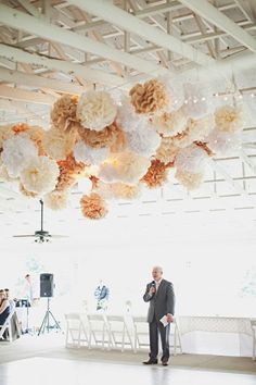 a man standing in front of a large chandelier with flowers hanging from it