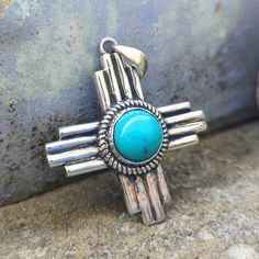 Turquoise Zia Pendant | Native American Jewelry | Handmade Zia Symbol Pendant | Zia Statement Jewelry | New Mexico Zia Necklace | Zia Sun Pendant | Mother's Day Gift | Sleeping Beauty Turquoise Pendant items : Pendant & Necklace Stone : Turquoise Shape : Zia Symbol Cut : cabochon  Material : 925 Sterling Silver Measurement : 1.5''x 1.5'' (inch) Zia Symbol : The Zia symbol consists of a circle with four groups of rays radiating from the center, forming a sun-like image. Each group typically has f Zia Jewelry New Mexico, Southwestern Turquoise Necklace For Western-themed Events, Handmade Turquoise Cross Necklace, Southwestern Style Silver Turquoise Necklace For Western-themed Events, Collectible Southwestern Turquoise Pendant Necklace, Bohemian Turquoise Cross Necklace, Zia Symbol, Friendship Day Gifts, Engagement Presents