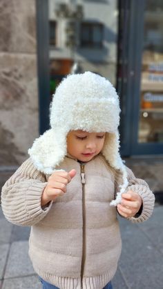 a small child wearing a white hat and jacket