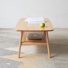 an apple sitting on top of a wooden table next to a book and laptop computer