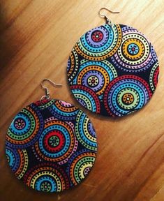 two pairs of colorful earrings sitting on top of a wooden table