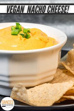 a white bowl filled with cheese next to tortilla chips on a black plate