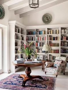 a living room filled with lots of books on top of a book shelf next to a table