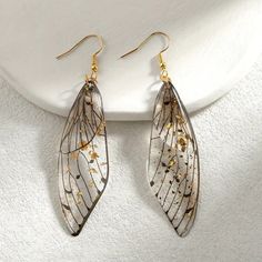 two pairs of gold and silver leaf earrings on a white plate with a white background