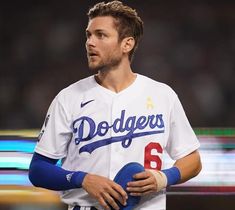 a dodgers baseball player holding a ball in his left hand and looking off to the side