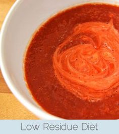 a white bowl filled with red sauce on top of a wooden table