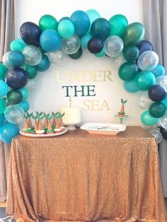 an under the sea party with balloons and desserts on a table in front of a sign