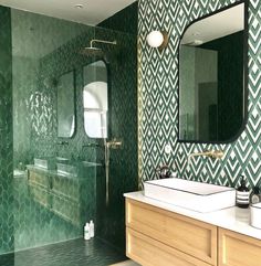 a bathroom with green tiles on the walls and counter tops, along with a large mirror