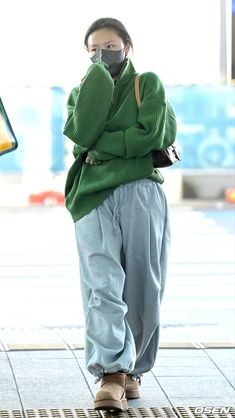 a woman wearing a face mask while standing on the sidewalk