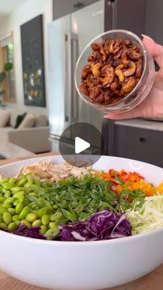 a person is pouring nuts into a bowl of salad