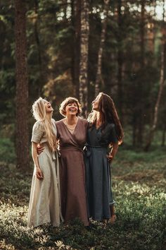 three women are standing in the woods and smiling at something they're talking to