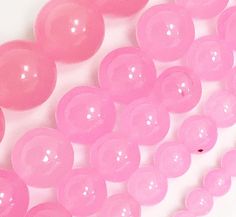 pink plastic beads are arranged on a white surface