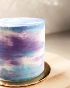 a blue and purple cake sitting on top of a wooden table