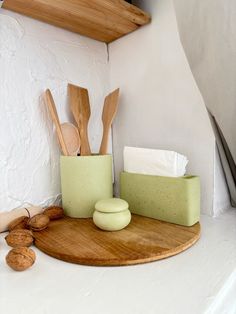 wooden utensils are sitting on a cutting board in front of a white wall