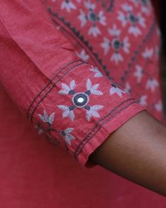 a close up of a person's arm wearing a red shirt with flowers on it