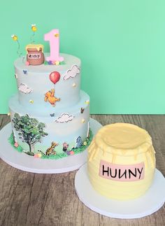 a birthday cake with winnie the pooh on it next to a one year old cake