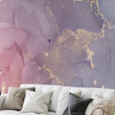 a white couch sitting in front of a wall with purple and gold paint on it