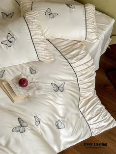 a white bed with butterflies on it and a book sitting on top of the pillow