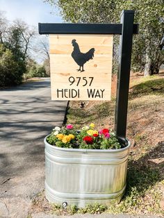 a sign that is sitting on the side of a road with flowers growing in it