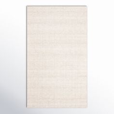 a white wall hanging on the side of a room with a light colored rug in front of it