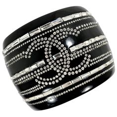 This important Chanel black resin and rhinestone cuff was released as part of the 2009 cruise collection. It is in excellent vintage condition and is simply stunning. What a wonderful item to show off in. It gives new meaning to the phrase "if you've got it flaunt it." Hinged on one side and stays closed with a small, round, hidden magnetic clasp on the inside. This oval shaped cuff fits a small to medium size wrist. Measures 2.13 inches wide (north to south). Marked CHANEL 09C MADE IN FRANCE. Chanel Cuff, Textures Fashion, Vintage Cuff Bracelet, Chanel Jumbo, Cruise Collection, Chanel Logo, Buckle Bracelet, Black Resin, Classy Fashion