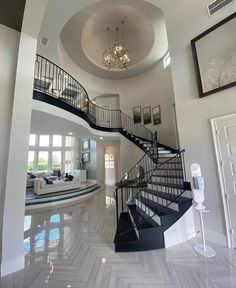 a spiral staircase in the middle of a living room with chandelier above it