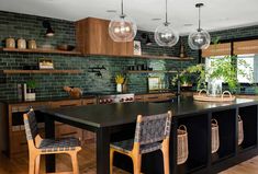 a kitchen with wooden cabinets and black counter tops, hanging lights above the island area