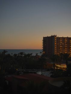 the sun is setting over an ocean front hotel