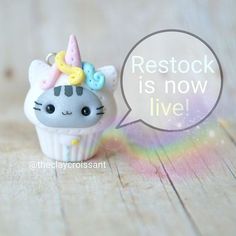 a small toy cat with a unicorn horn on it's head sitting next to a rainbow