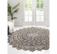 a large round rug on the floor in front of a window with white walls and doors