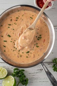 a wooden spoon in a pot filled with sauce and garnished with parsley