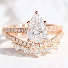 two wedding rings with a pear shaped diamond in the center and side stones on each band