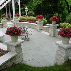 an outdoor patio with benches and flowers in the planter boxes on each side of the walkway